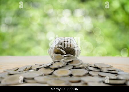 Einsparung für das zukünftige Konzept. Eine gläserige Schweinebank mit Münzen stapelte sich viel auf dem Tisch. Planung, Investmentfonds, finanzielle Erträge aus Dividenden, in Stockfoto