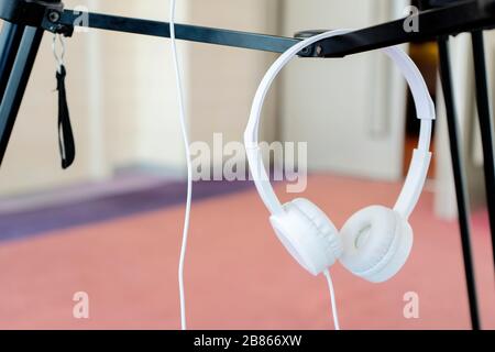 Weiße Kopfhörer sind auf einem Stativ aufgehängt. Gebrauchsfertig ist ein wichtiges Gerät für Videoaufnahmen. Stockfoto