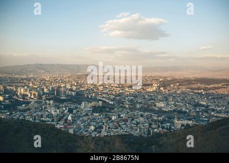 Schöner Panoramablick auf Tiflis, Georgien. Die Stadt in der Nähe der Berge gegen den Himmel mit Wolken. Stockfoto