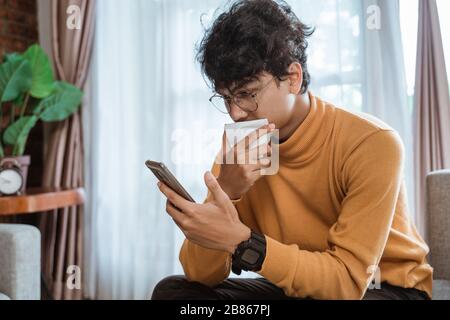 Kranker Mann hustet, während er auf einer Couch sitzt Stockfoto