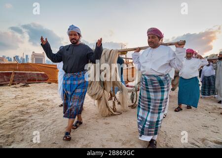 Traditionelle arabische Fischer arbeiten in Katara Strand Doha, Katar mit Daus im Wasser und Wolken am Himmel im Hintergrund. Stockfoto