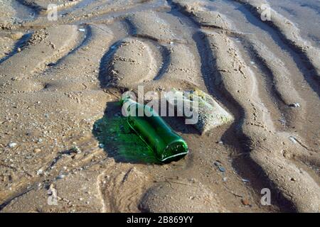 Ausrangierte transparente Flasche am Strand zeigt die Verschmutzung der Meere durch Müll. Stockfoto