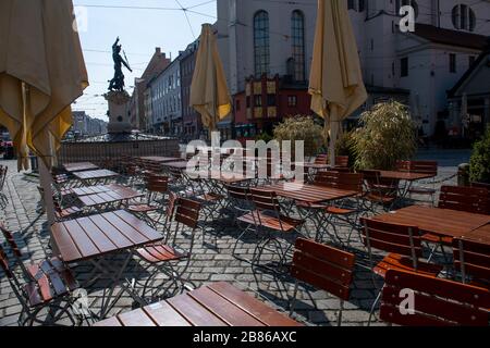 Augsburg, Deutschland. März 2020. Vor dem Merkurbrunnen an der Maximilian-anstraße sind am späten Morgen Tische und Stühle eines Straßencafés desertiert. Kredit: Stefan Puchner / dpa / Alamy Live News Stockfoto