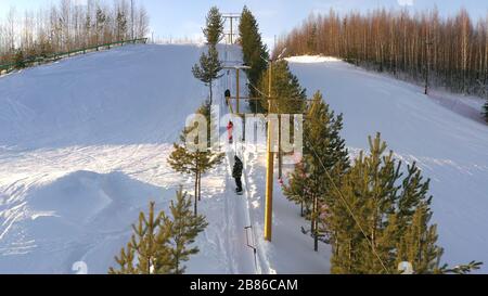 Skilifte dauern hellen Wintertag. Skifahrer und Snowboarder klettern mit einem Skilift auf den Berg Stockfoto