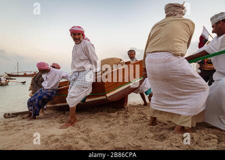 Traditionelle arabische Fischer arbeiten in Katara Strand Doha, Katar mit Daus im Wasser und Wolken am Himmel im Hintergrund. Stockfoto