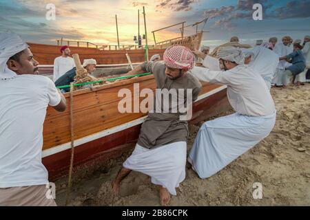 Traditionelle arabische Fischer arbeiten in Katara Strand Doha, Katar mit Daus im Wasser und Wolken am Himmel im Hintergrund. Stockfoto