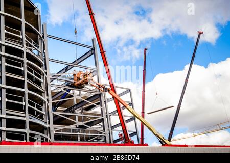 Kräne und Kirschpflücker beim Bau eines Neubaus mit Stahlfachwerkkonstruktion im Einsatz. Nottingham, England, Großbritannien Stockfoto