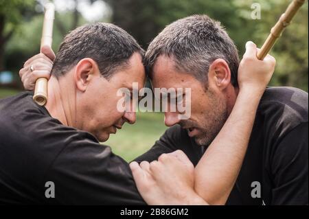 Filipino escrima arnis Instruktor und Student Practice Stick Fight Choke Techniken auf dem Kapap Martial Arts Seminar Stockfoto