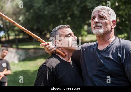 Filipino escrima arnis Instruktor und Student Practice Stick Fight Choke Techniken auf dem Kapap Martial Arts Seminar Stockfoto