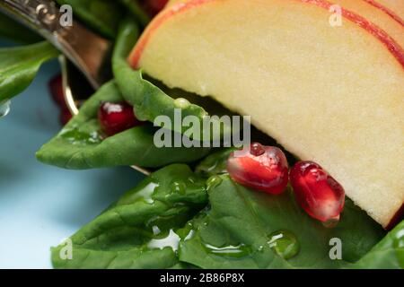 Makrofoto. Tropfen Honig in einem Obstteller. Spinat Obstsalat mit Granatapfelsamen Stockfoto