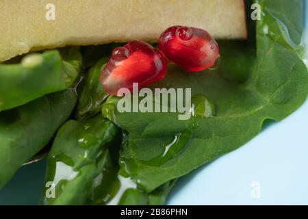 Makrofoto. Tropfen Honig in einem Obstteller. Spinat Obstsalat mit Granatapfelsamen Stockfoto