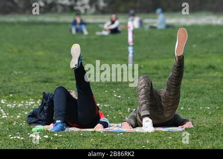 20. März 2020, Hessen, Frankfurt am Main: Ein Paar turnt auf einer Wiese im Frankfurter Günthersburgpark. Foto: Arne Dedert / dpa Stockfoto