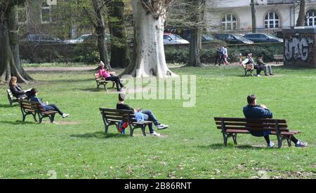 20. März 2020, Hessen, Frankfurt am Main: Die Menschen genießen das sonnige Frühlingswetter auf Bänken im Frankfurter Günthersburgpark. Foto: Arne Dedert / dpa Stockfoto