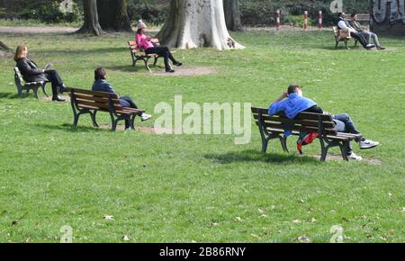 20. März 2020, Hessen, Frankfurt am Main: Die Menschen genießen das sonnige Frühlingswetter auf Bänken im Frankfurter Günthersburgpark. Foto: Arne Dedert / dpa Stockfoto