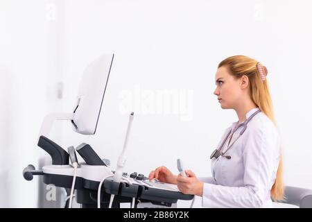 Junge blonde Arzt arbeiten am Ultraschallgerät in der neuen Klinik. Helthcare Konzept. Stockfoto