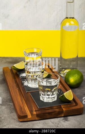 Tequila-Flasche und Schüsse, Limes, Salz auf Holzbrett Stockfoto