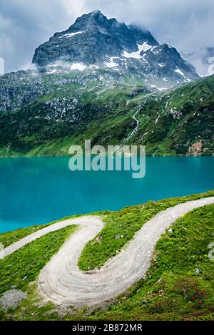 Kurvenreicher Weg in den Alpen mit einem Berg im Hintergrund Stockfoto