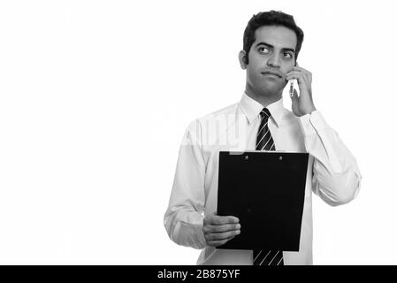 Junge persische Geschäftsmann Gespräch am Handy und Halten der Zwischenablage beim Denken Stockfoto