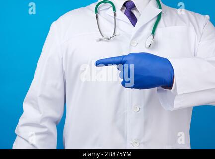 medic man in weißem Mantel mit Knöpfen, an Händen mit blauen sterilen Handschuhen, zeigt Handgeste, die auf das Motiv hinweist, weißer Hintergrund Stockfoto