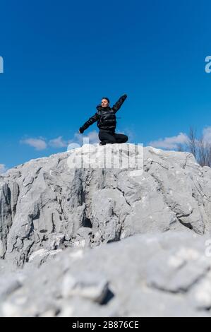 Mädchen mit weit geöffneten Armen auf einem felsigen Berg Stockfoto