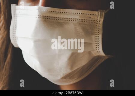 Detail des nicht erkennbaren Gesichts der Frau, das eine weiße medizinische Gesichtsmaske trägt. Teilweise verschwommen an den Kanten. Coronavirus, COVID-19 Quarantäne. Maske als Schutz. Arzt, Pflegekonzept. Stockfoto