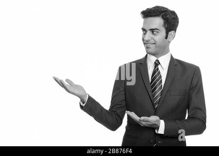 Porträt eines fröhlichen jungen persischen Kaufmanns im Anzug, der etwas zeigt Stockfoto