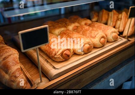 Brötchen mit Wurstbrötchen, das auf Holztablett im Schrank verkauft wird Stockfoto