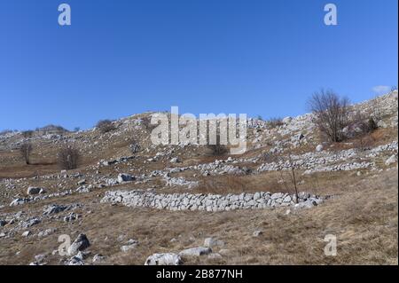 Alte rustikale Steinmauer bleibt im wilden Gelände in den Bergen zurück Stockfoto