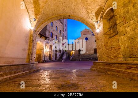 San Gimignano, Toskana: Palazzo Comunale, Torre Grossa und Duomo, eingerahmt von einem Bogen des Palazzo Vecchio del Podestà auf der Piazza del Duomo. Stockfoto