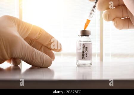 Gerillte Hände bereiten Dosis des Coronavirus Impfstoffs auf weißem Tisch isoliert vor. Vorderansicht. Horizontale Zusammensetzung. Stockfoto