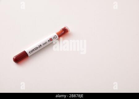 Reagenzglas mit Blutprobe infizierter Kovid 19 auf weißem Tisch. Ansicht von oben erhöht. Stockfoto