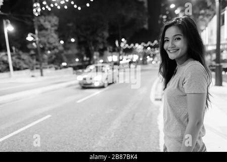 Junge schöne asiatische Frau, die nachts in den Straßen der Stadt umherstreift Stockfoto