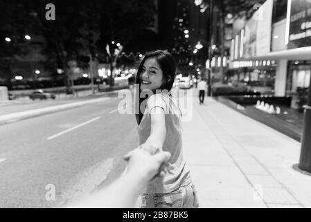 Junge schöne asiatische Frau, die nachts in den Straßen der Stadt umherstreift Stockfoto