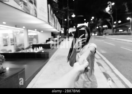 Junge schöne asiatische Frau, die nachts in den Straßen der Stadt umherstreift Stockfoto