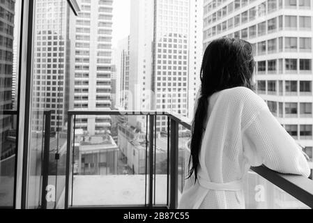 Junge, schöne asiatische Frau, die vom Balkon aus den Blick auf die Stadt genießt Stockfoto