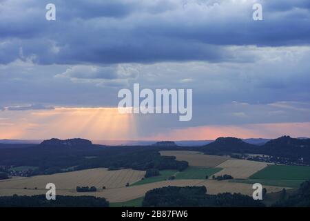 Dramatische Landschaft bei Sonnenuntergang in der Sächsischen Schweiz, Deutschland mit dunklen Wolken und goldenen Sonnenstrahlen Stockfoto