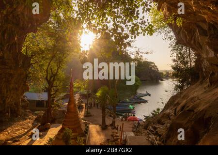 Schöner und farbenfroher Blick auf einen See mit Booten bei Sonnenuntergang am Ausgang einer Höhle in hPa-an, Myanmar. Stockfoto