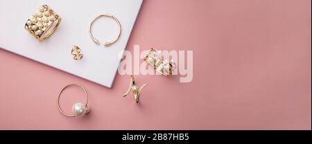 Draufsicht über goldene und perlige Armbänder auf rosa und weißem Hintergrund mit Kopierraum Stockfoto