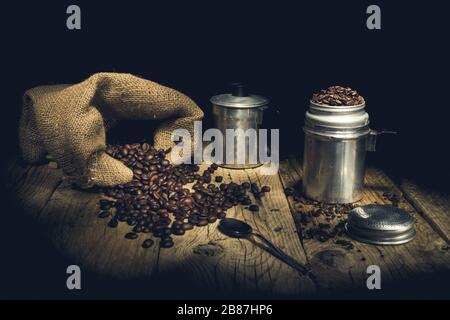 Kaffeebohnen in der alten Kaffeekanne auf Holztisch. Stockfoto