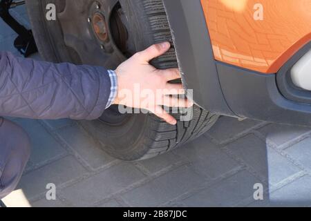 Fahrer, der ein Rad eines modernen Autos wechselt. Beschädigter Autoreifen. Räder ausgleichen oder reparieren und Reifen wechseln. Reparaturkonzept für Fahrzeuge. Stockfoto