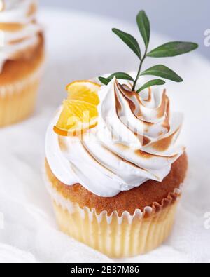 Hausgemachte Cupcakes mit Zitrone und Blättern auf weißem Hintergrund Stockfoto