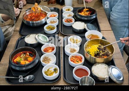 Verschiedene koreanische Speisen mit würziger Suppe, Kimchi, Nudeln und Gemüsepflücker auf dem Tablett im Restaurant Stockfoto