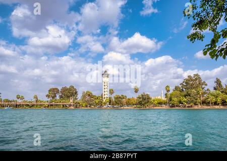 Blick auf den Uhrturm Yuregir vom Adana Central Park in der Provinz Adana. Seyhan River und Suspension Bridge Stockfoto