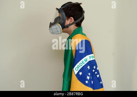 Rio de Janeiro, Brasilien, 20. März 2020. Kind trägt Gesichtsschutzmaske gegen Gase und Gerüche, die in die brasilianische Flagge gehüllt sind. Stockfoto