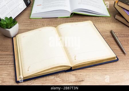 Öffnen Sie das Notebook mit Stift für Ihren Text im Hintergrund. Öffnen Sie das Buch, und Bücher hängen am Arbeitsplatz, der zum Schreiben bereit ist. Stockfoto