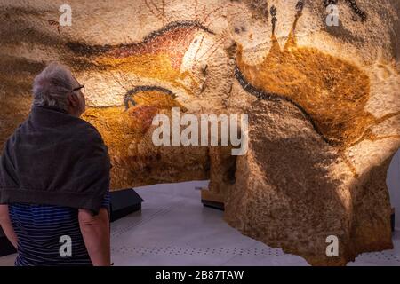 Ein Besucher blickt auf eine Nachbildung eines prähistorischen Höhlenmales im Lascaux Centre in Montignac, Frankreich. Stockfoto