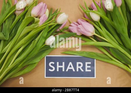 Draufsicht auf Spring Themenkomposition mit pastellrosa Tulpen und EINEM GEMEINSAMEN Schild, auf dem Tisch im Blumenladen Stockfoto