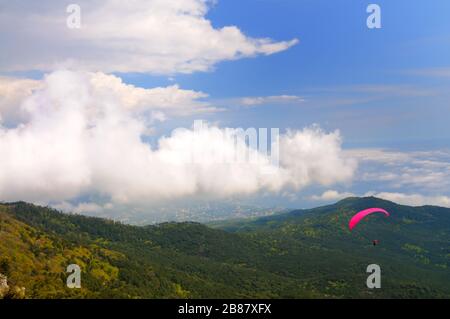 Extreme Erholung, Fallschirmspringer fliegt über die Berge und Felsen. Weiße Wolken am Himmel Stockfoto