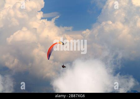 Extreme Erholung, Fallschirmspringer fliegt über die Berge und Felsen. Weiße Wolken am Himmel Stockfoto