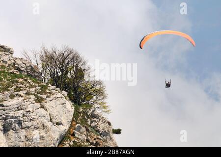 Extreme Erholung, Fallschirmspringer fliegt über die Berge und Felsen. Weiße Wolken am Himmel Stockfoto